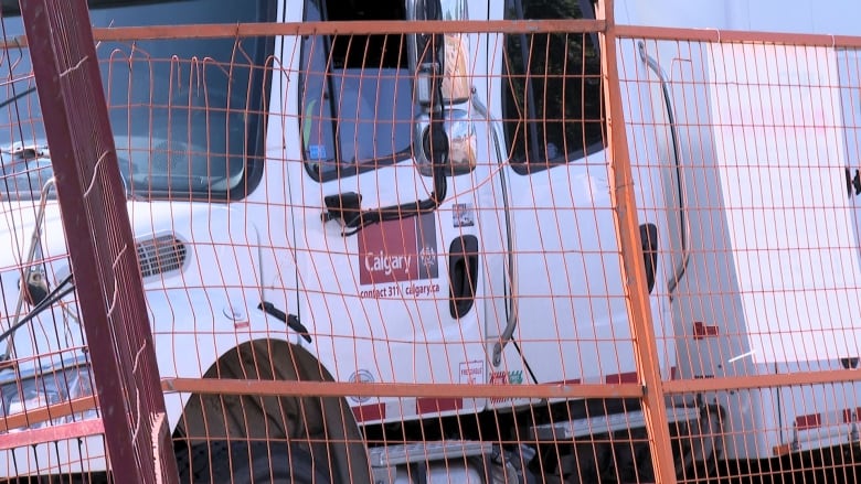 a white truck behind an orange metal fence. the truck reads 