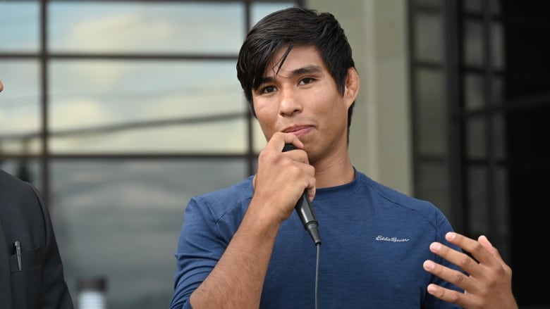 a man stands in front of a courthouse with a mic