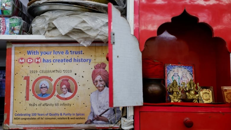 A carton displaying the Indian spice manufacturing company MDH's centenary celebration is placed next to a home temple at a shop in the old quarters of Delhi, India, in May.