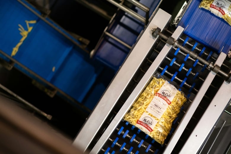 A bag of frozen fries is seen rolling along a conveyor belt at a factory.