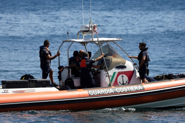 About a half-dozen people are shown on a small boat patrolling a large body of water, with life vests visible.