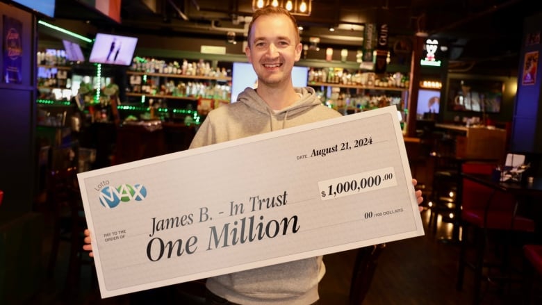 A man holds the cheque for the winning lottery showing $1 million.