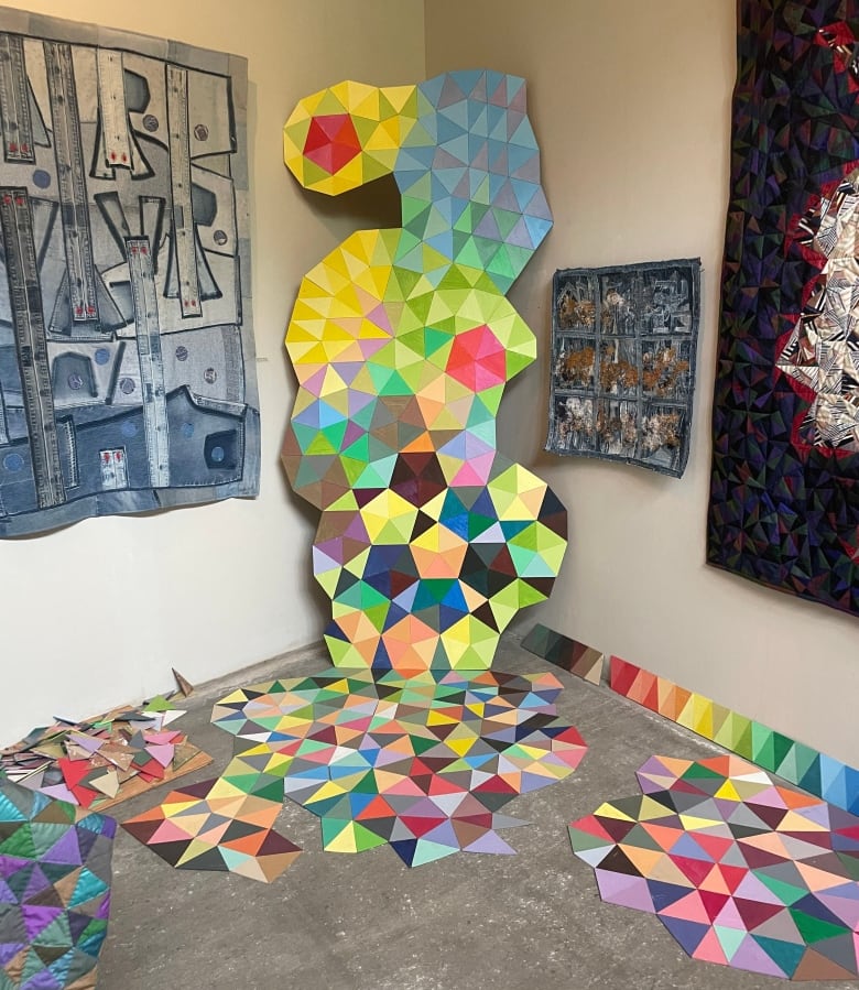 Quilts and other textile works hang around the studio, while a bold geometric sculpture climbs from the floor and up the wall. 