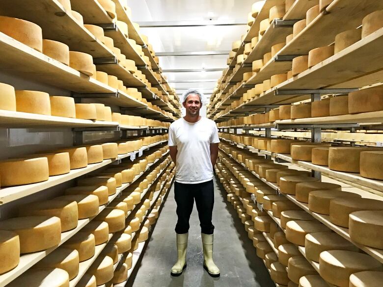 A man stands in between aisles of cheese.