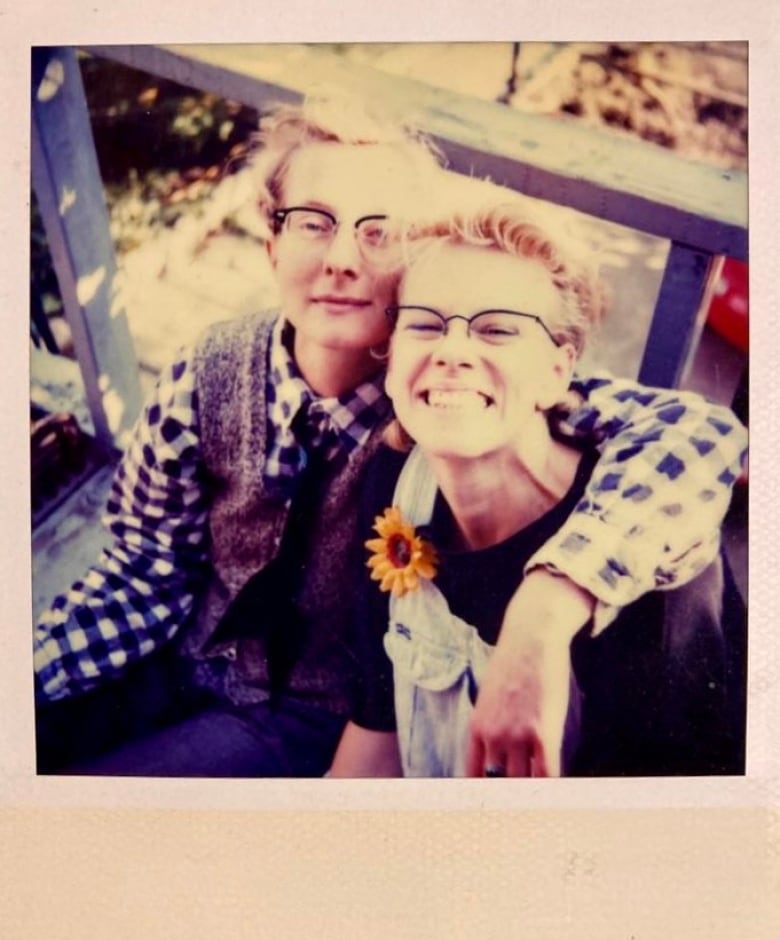 A polaroid photo of two women smiling outdoors.