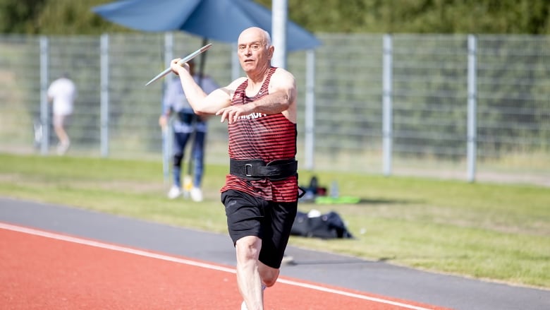 a man throws a javelin pole on a track