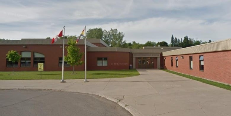 A long brown school with two flag poles in front