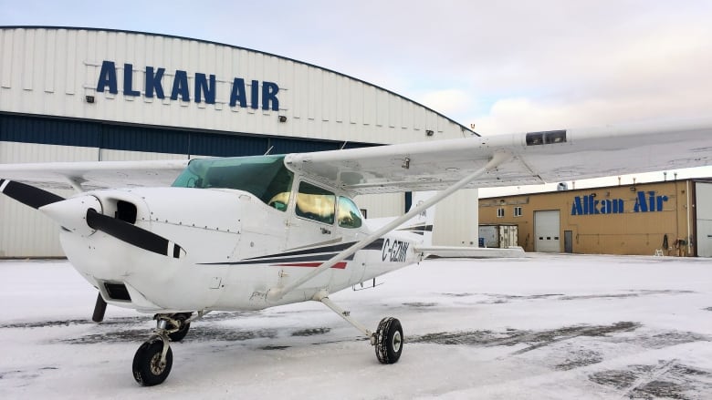 A small plane sits on the tarmac of a snowy small airport