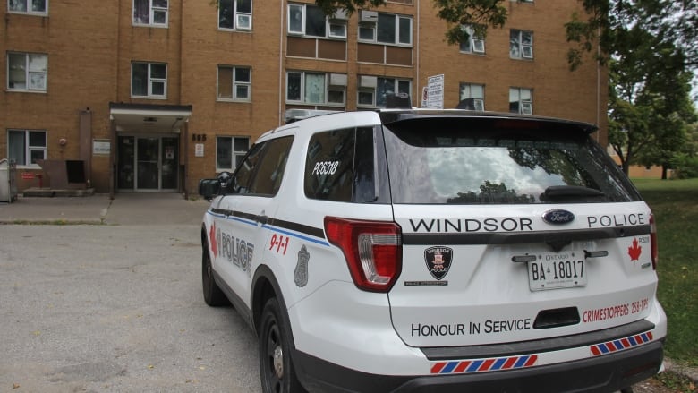 A Windsor police cruiser in front of a brick building.