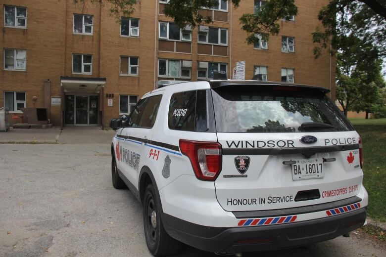 A Windsor police cruiser in front of a brick building.