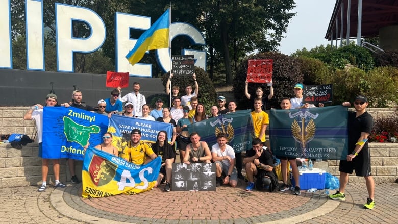 People holding multiple banners and Ukrainian flags pose for a picture.