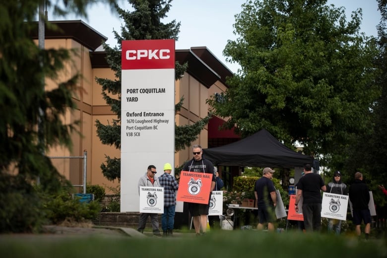 Demonstrators carry signs that are tied around their necks as they gather outside a building.