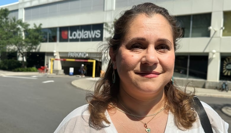 A woman stands in front of Loblaws. 