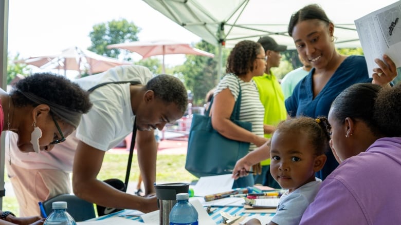 Two people fill out surveys at a table under a tent at the event. 