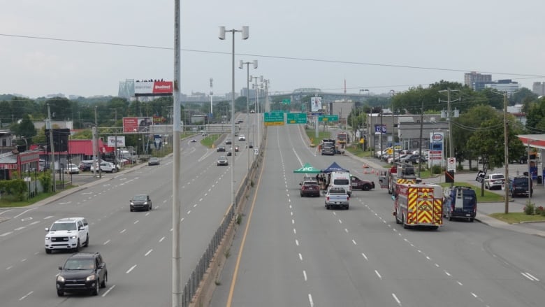 An artery road. The lanes on the right are closed to circulation where firefighters, police and other workers are gather to try to deal with the source of a gas leak.