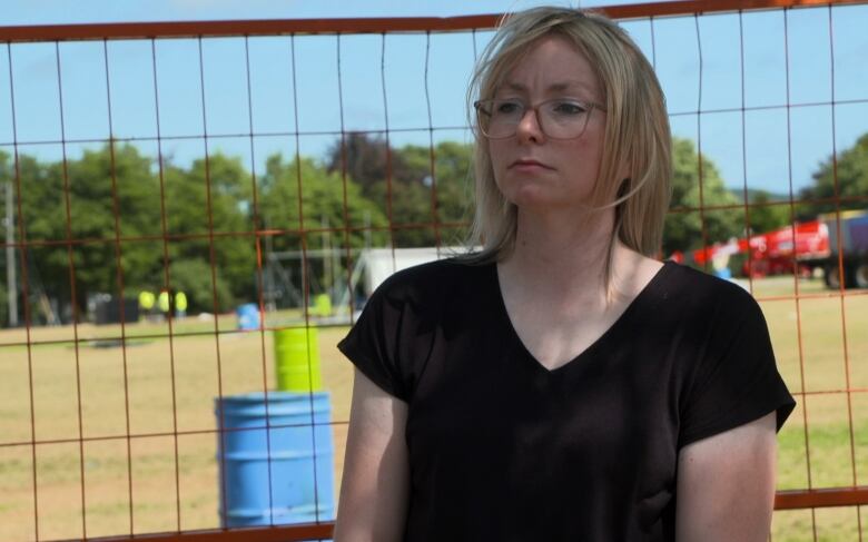 Blonde woman stands in front of wire fence