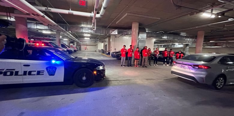 A police car pulling over a sedan, while people watch.