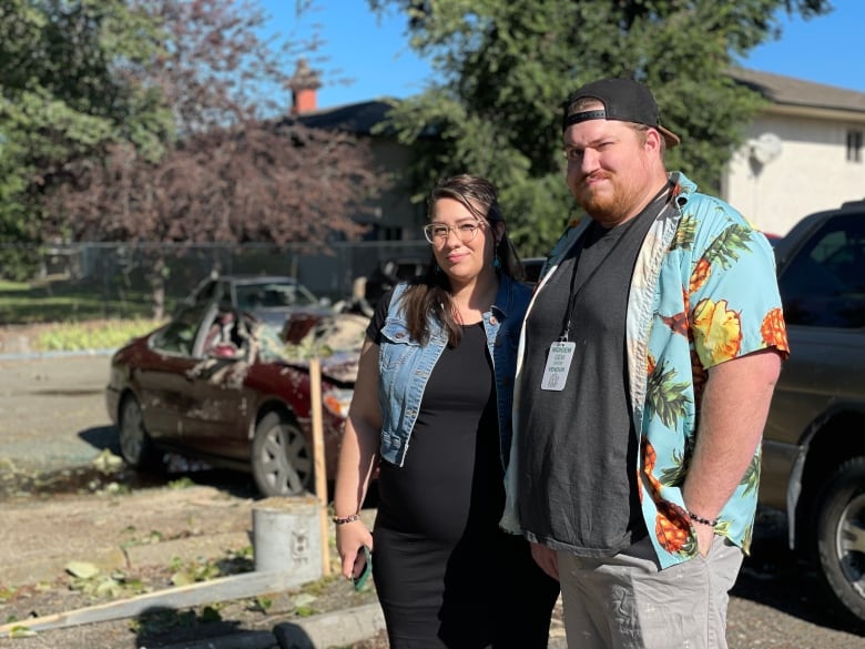 Two people stand in a parking lot.