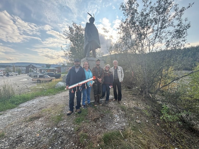 A group of people standing infront of a statue