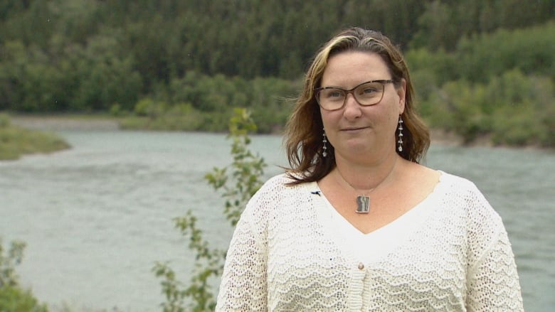 A woman stands in front of a river.