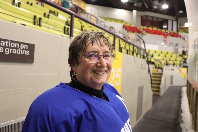 A woman smiles in hockey equipment