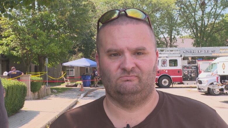 A close-up of a man with a fire truck behind him.