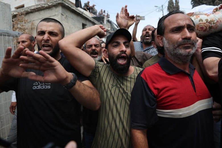 A group of men are seen waving their arms and yelling emotionally. 