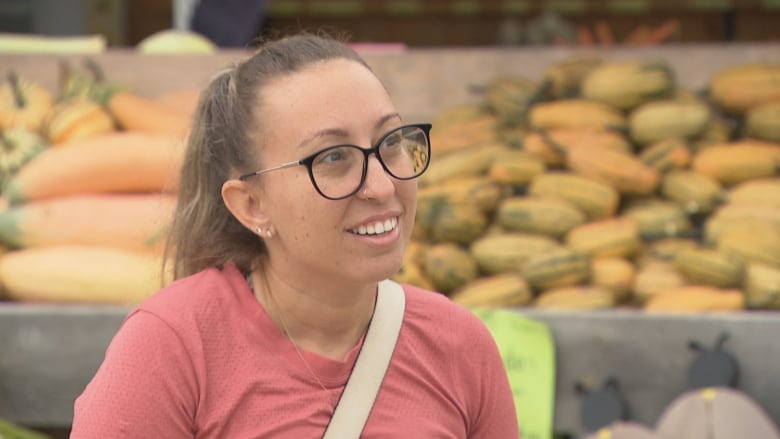 A woman with glasses and a pink shirt.