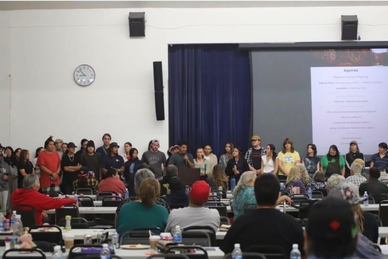 A row of young people stand beside a speaker at a conference. 