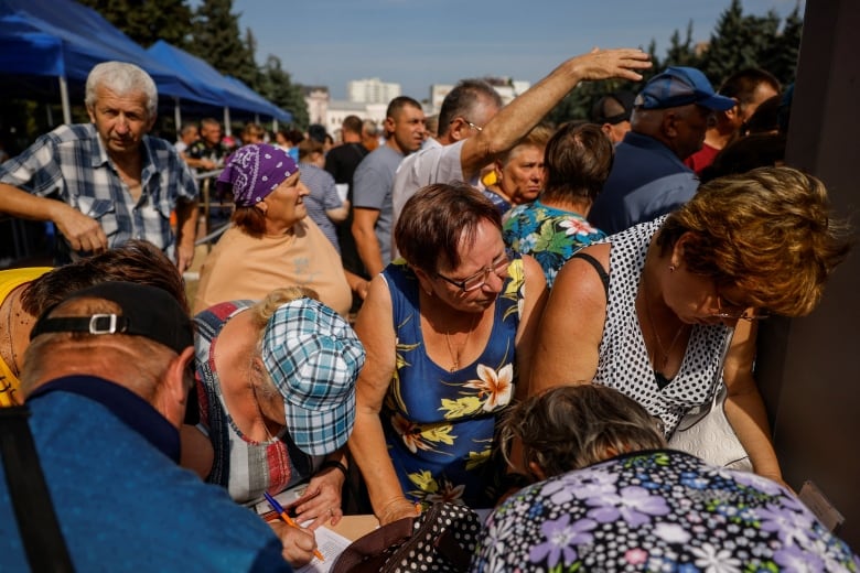 People queue at a humanitarian aid distribution center for residents, who were evacuated from the Kursk region.