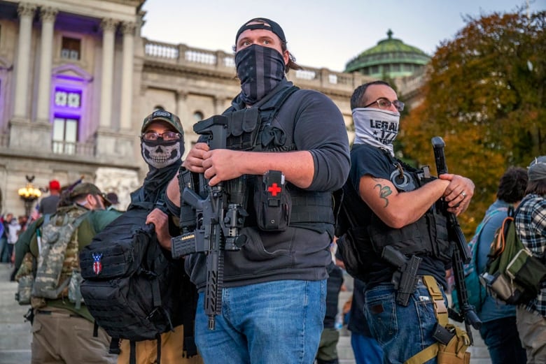 Men wearing face masks and carrying rifles