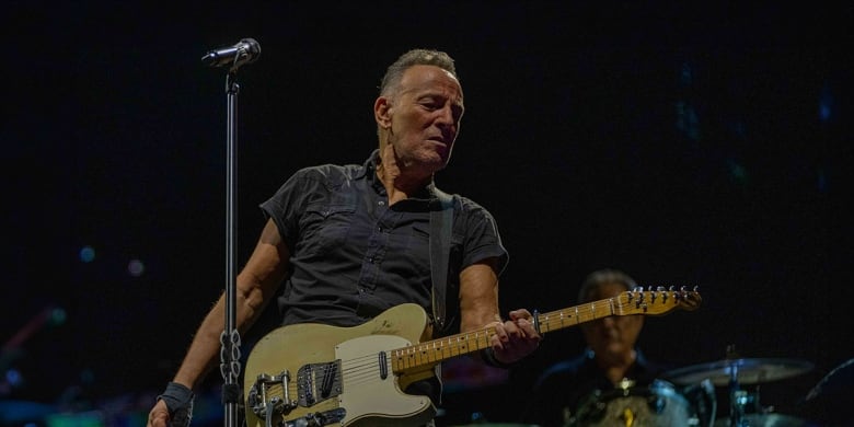 A man plays a telecaster guitar onstage. 