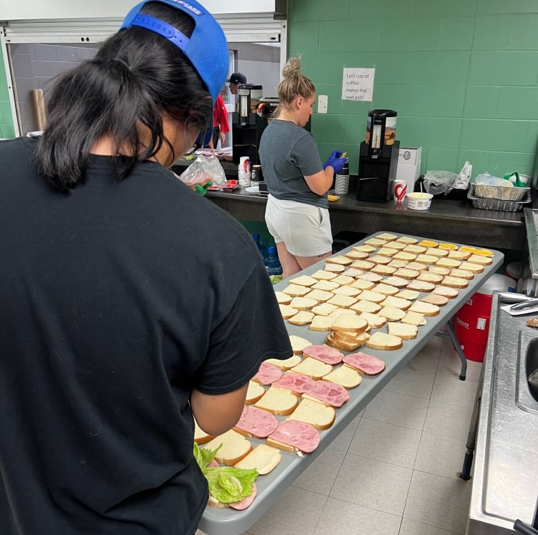 people are making sandwich that lay on a table in the middle of the room