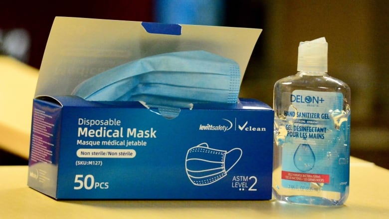 A 50 pc box of medical face masks sitting next to a bottle of DELON+ hand sanitizer.