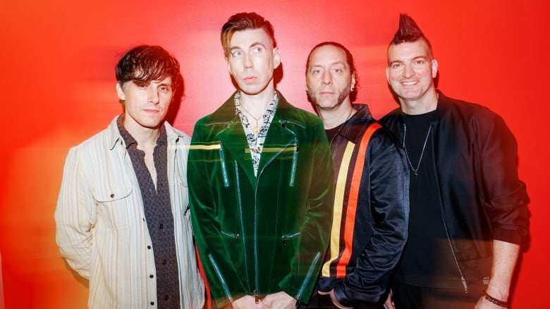 Four people pose in front of a red wall