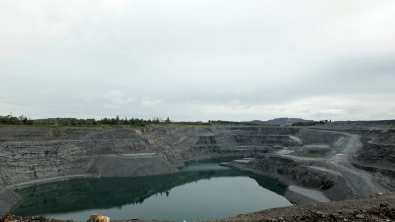 A large open pit mine with a lake of water in the bottom.