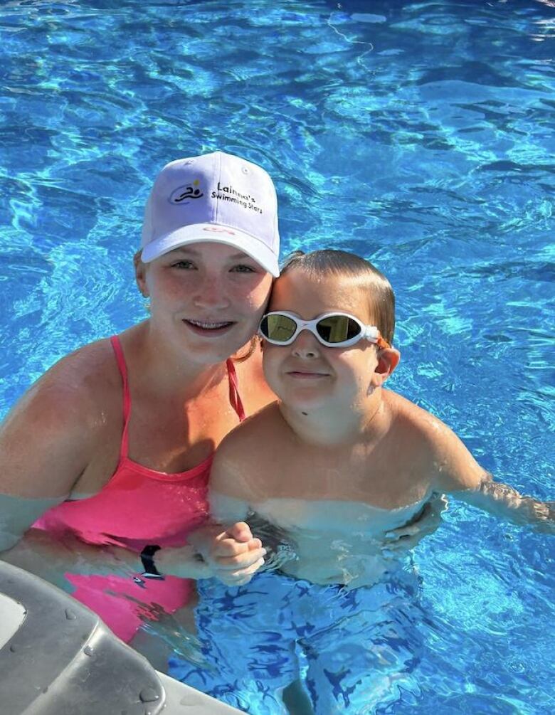 a girl and boy smile at camera in a pool