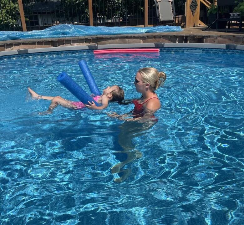 a girl helps a young boy swim in a pool