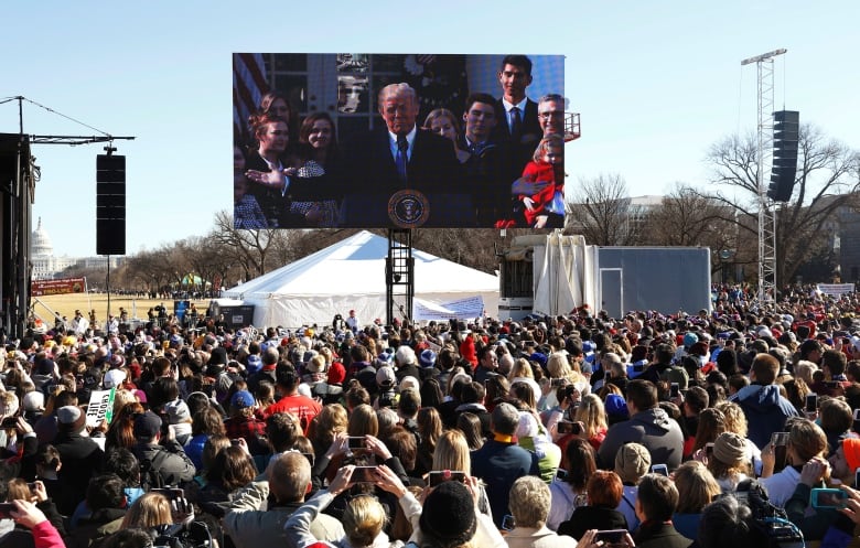 Trump on screen in front of crowd