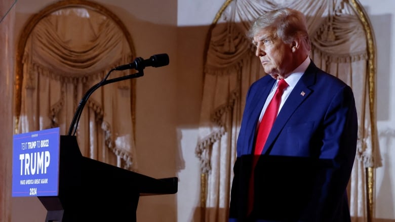 Trump, standing near podium in ornate ballroom