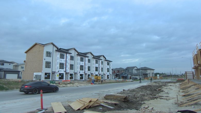 Buildings are under construction on both sides of a paved road.