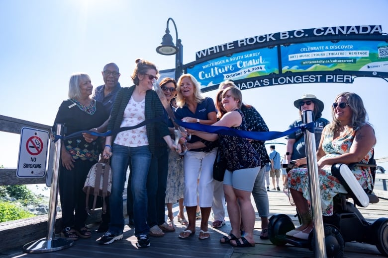 A group of people cut a blue ribbon.