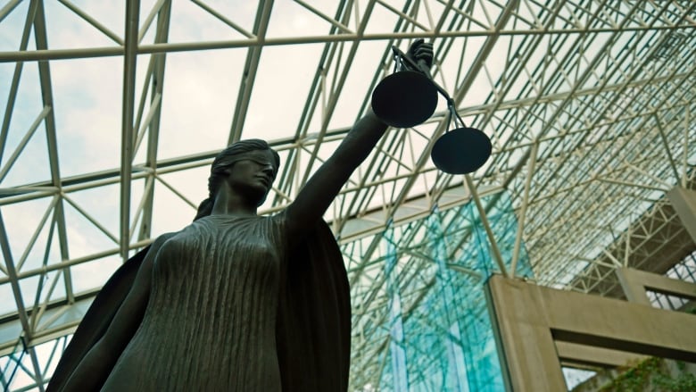 A statue of a blind goddess holding the scales of justice is pictured in an outdoor atrium.