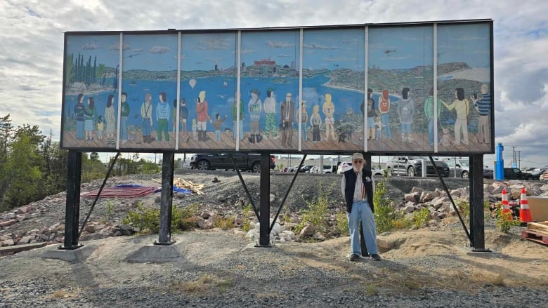 Man stands beside Mural