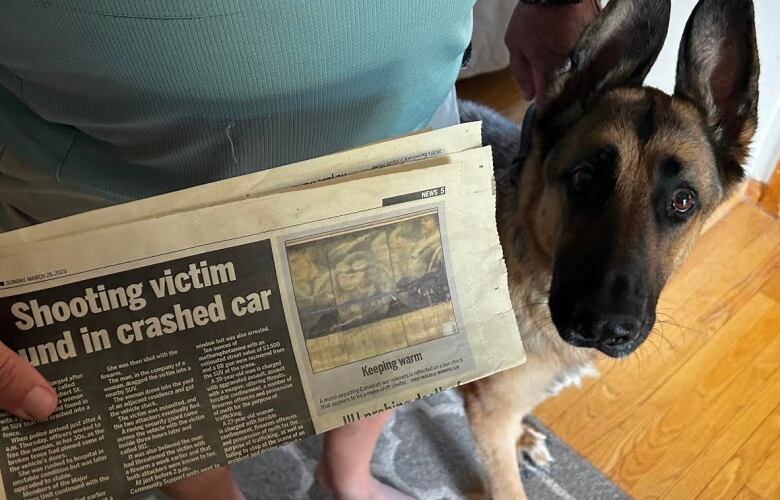 A man holding a newspaper with a dog by his side