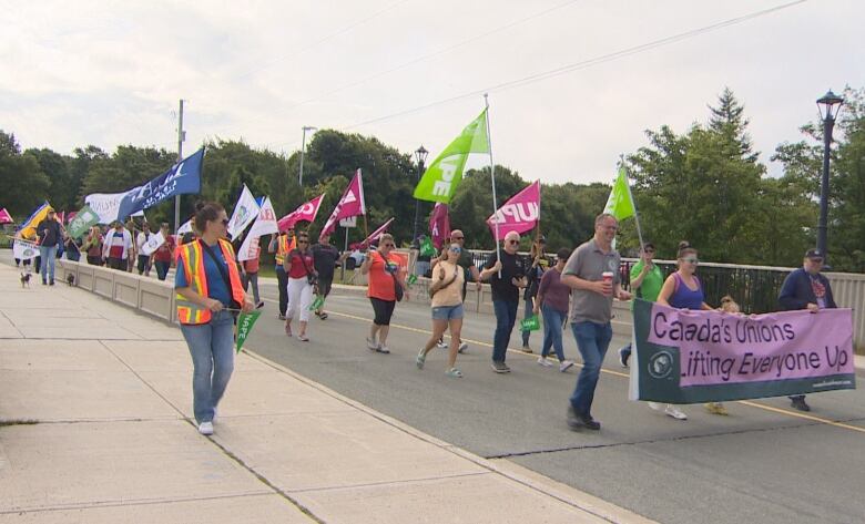 A crowd of people walk with flags and banners.