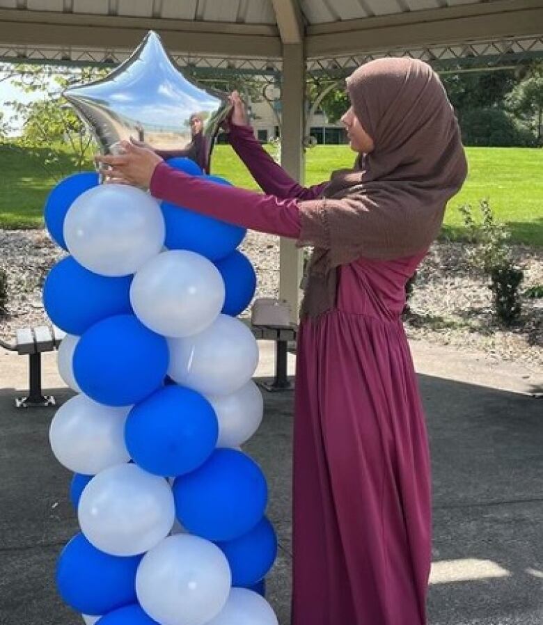 A Muslim woman arranges a display of party balloons.