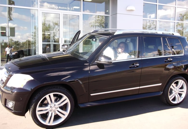 A woman sits in a luxury car.