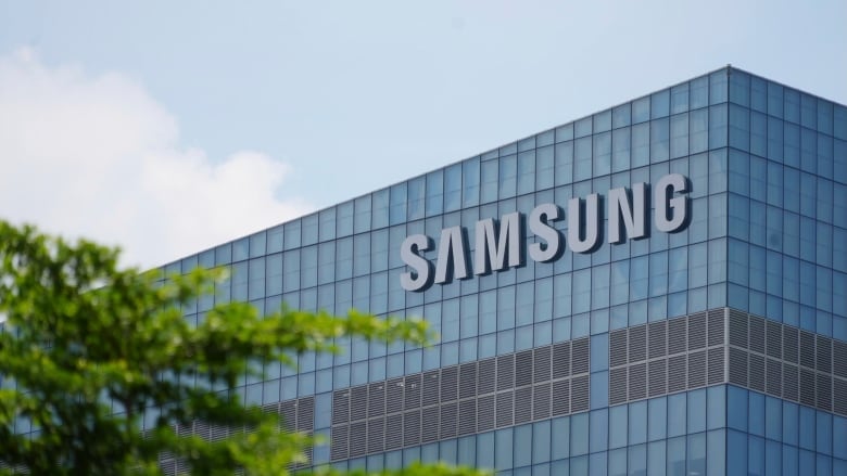 A blue Samsung logo is seen on a glass high-rise building on a sunny day.