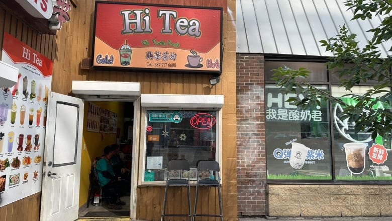 A small bubble tea shot has its door open and customers are sitting inside.